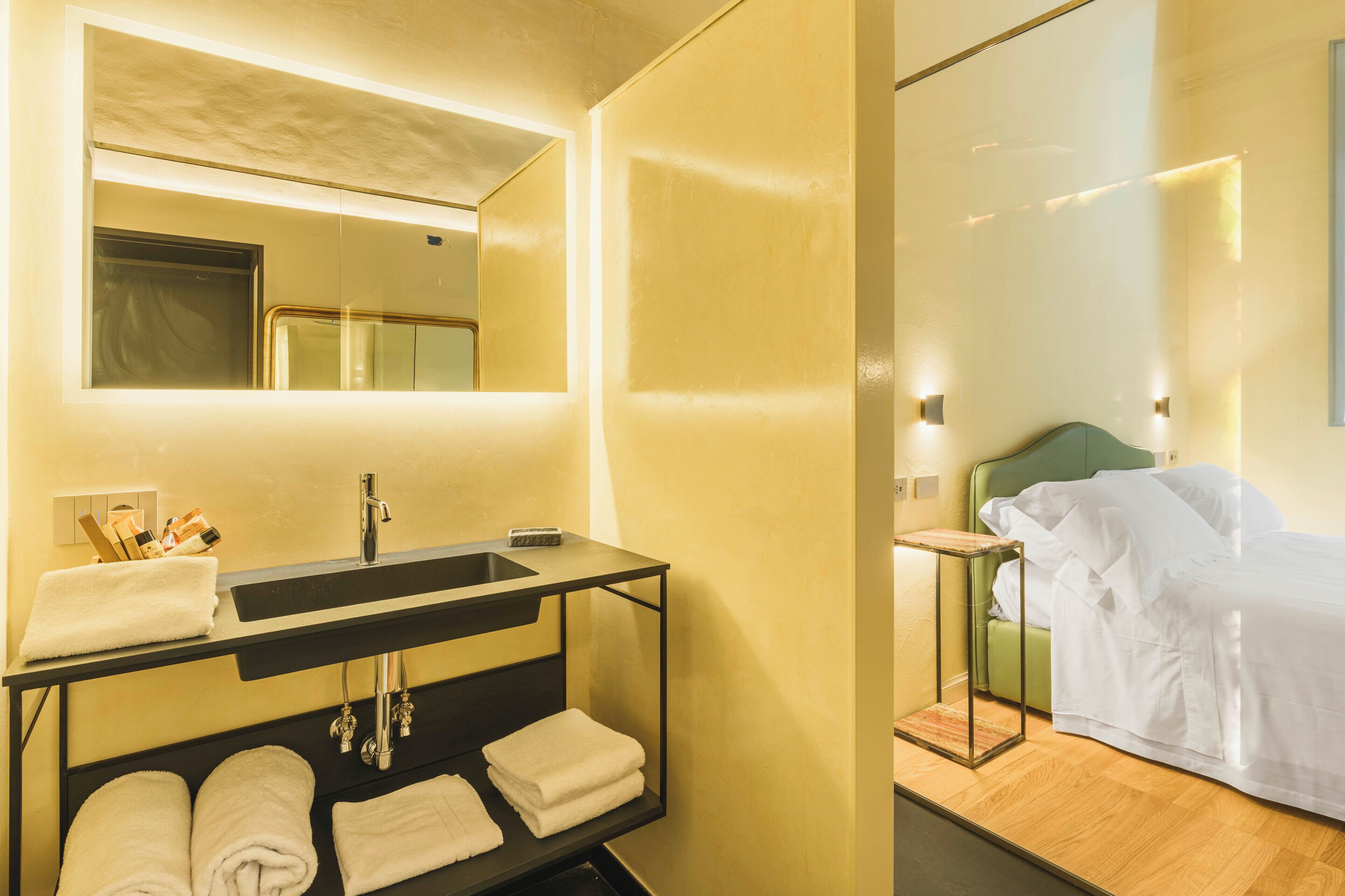 Un baño moderno con un espejo grande, lavamanos y espacio para toallas.