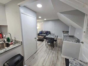 A compact kitchen with a sink, countertop, and a dining area with a table and chairs.