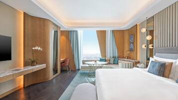 Una moderna camera d'albergo con un ampio letto, una scrivania, un angolo salotto e vista sulla città.