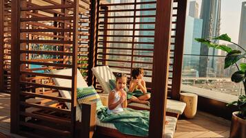 A balcony with wooden furniture and a city view.
