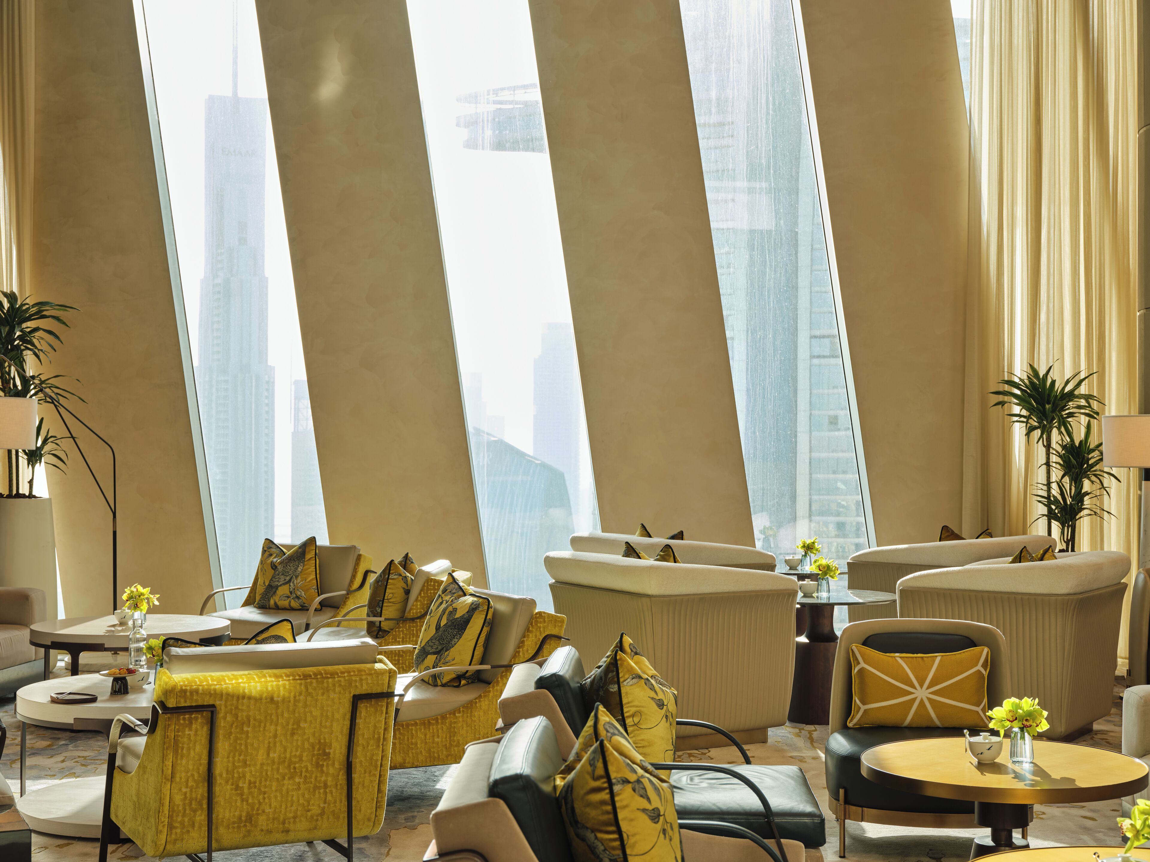 A modern hotel lobby with high-rise buildings in the background, comfortable seating areas, and decorative plants.