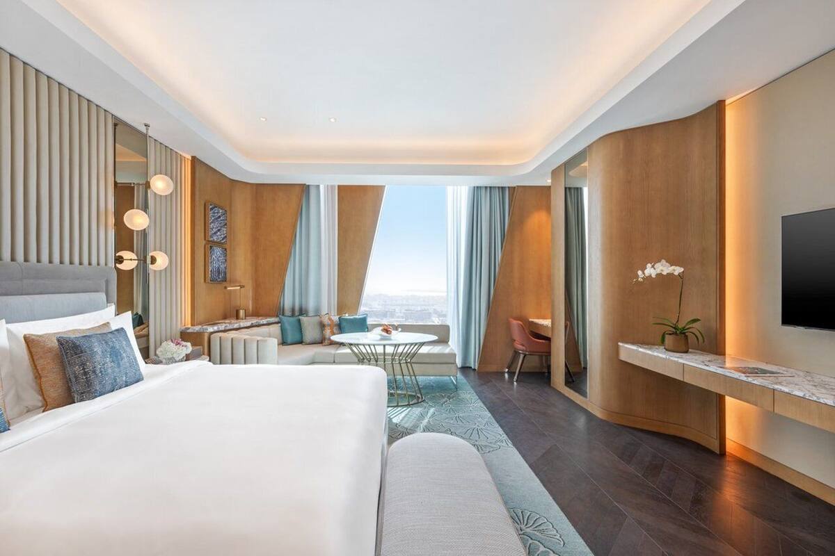 Une chambre d’hôtel moderne dotée d’un grand lit, d’un bureau, d’un coin salon et d’une télévision.