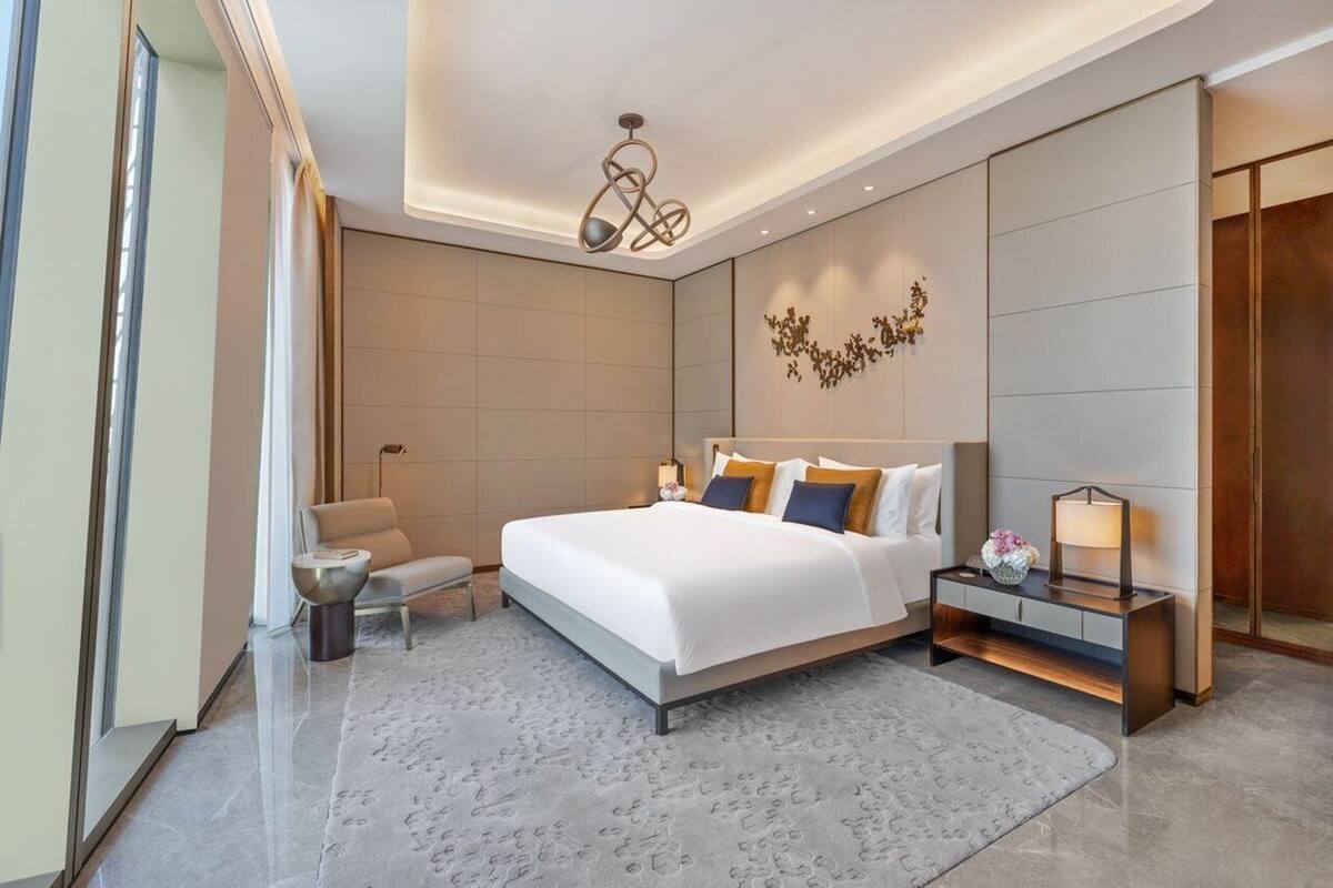 Une chambre d’hôtel moderne dotée d’un grand lit, d’un coin salon et d’une table de chevet avec une lampe.