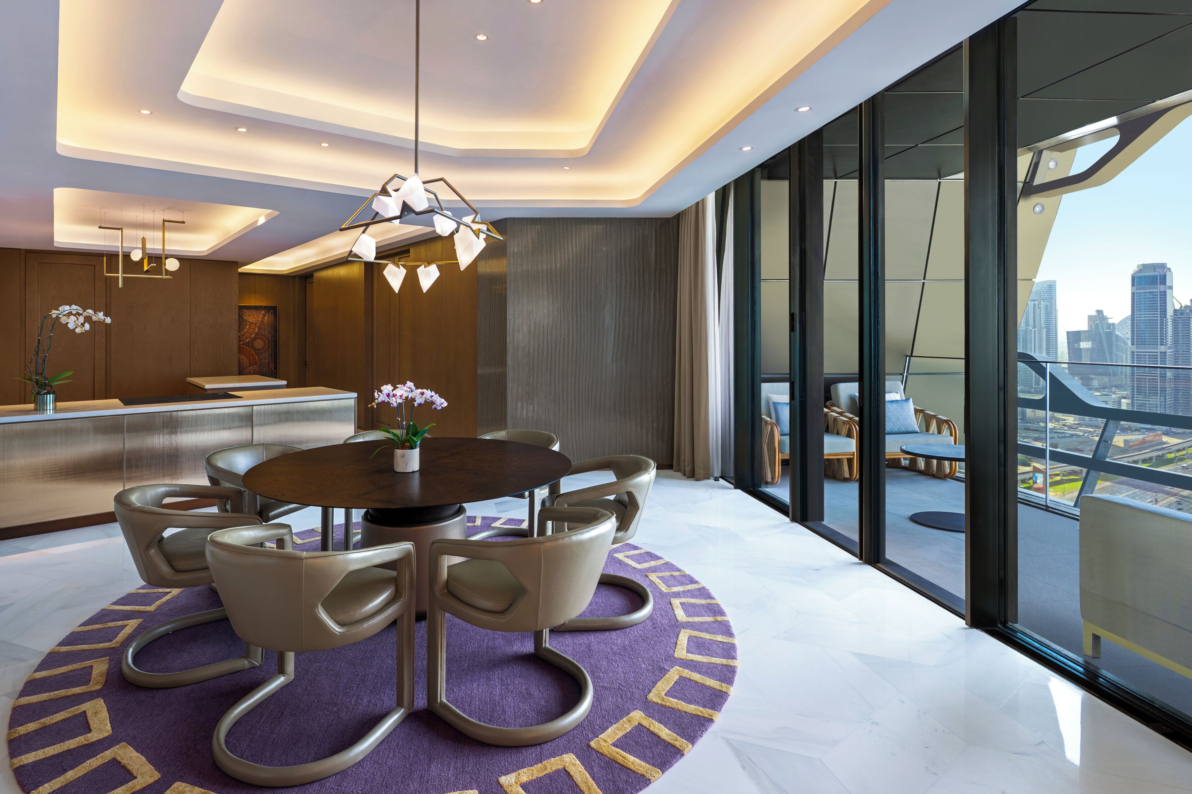 A modern hotel room with a dining area, large windows with a city view, and contemporary furniture.