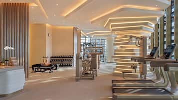 A modern gym with treadmills, weight machines, and dumbbells.
