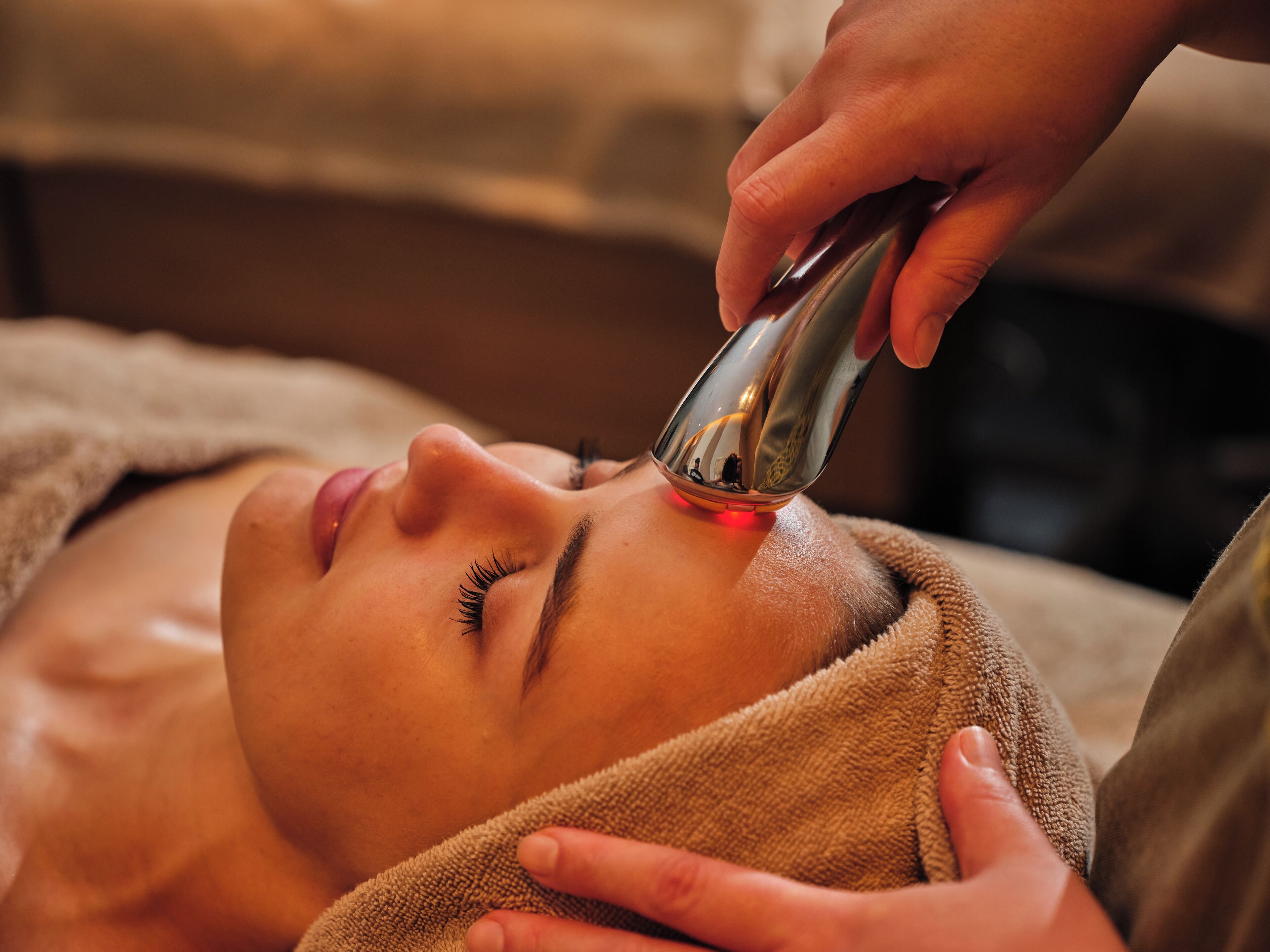 A person lying down with a device being used on their face.