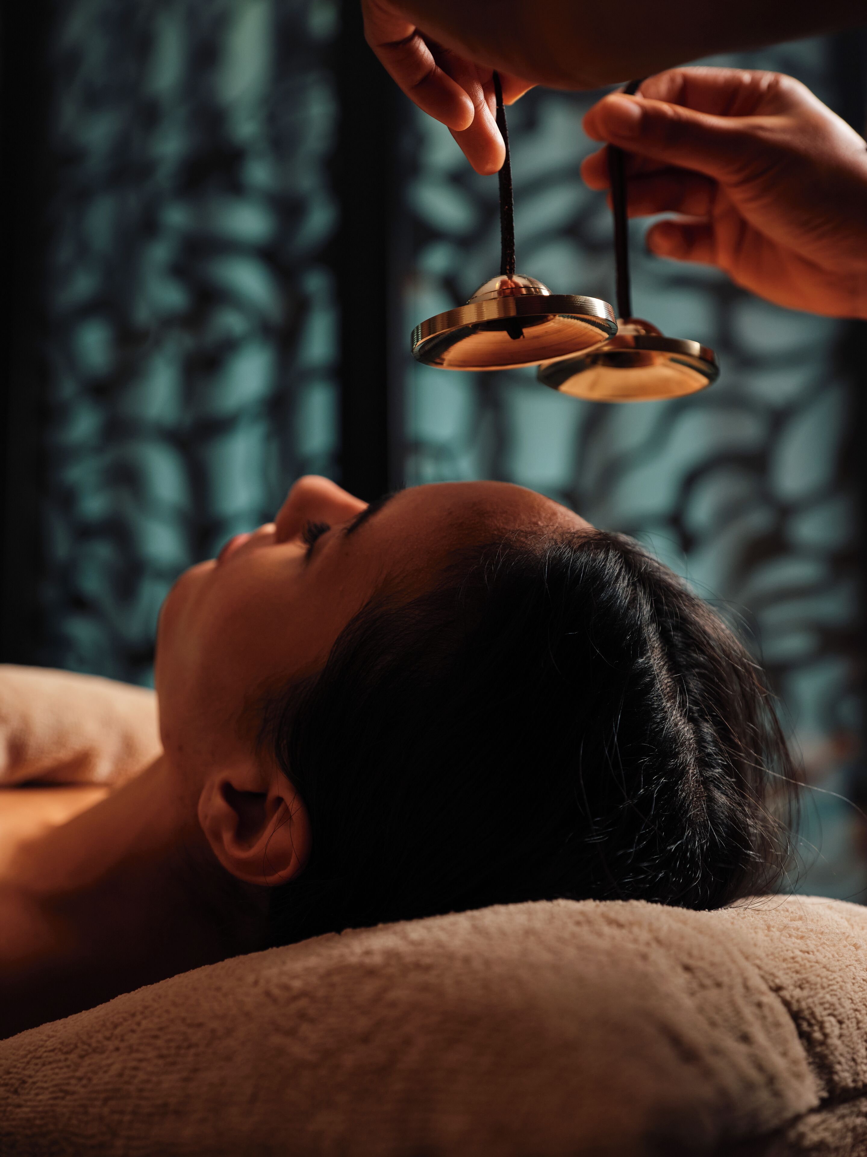 Een persoon ligt neer terwijl een massagetherapeut een apparaat op hun hoofd aanbrengt.