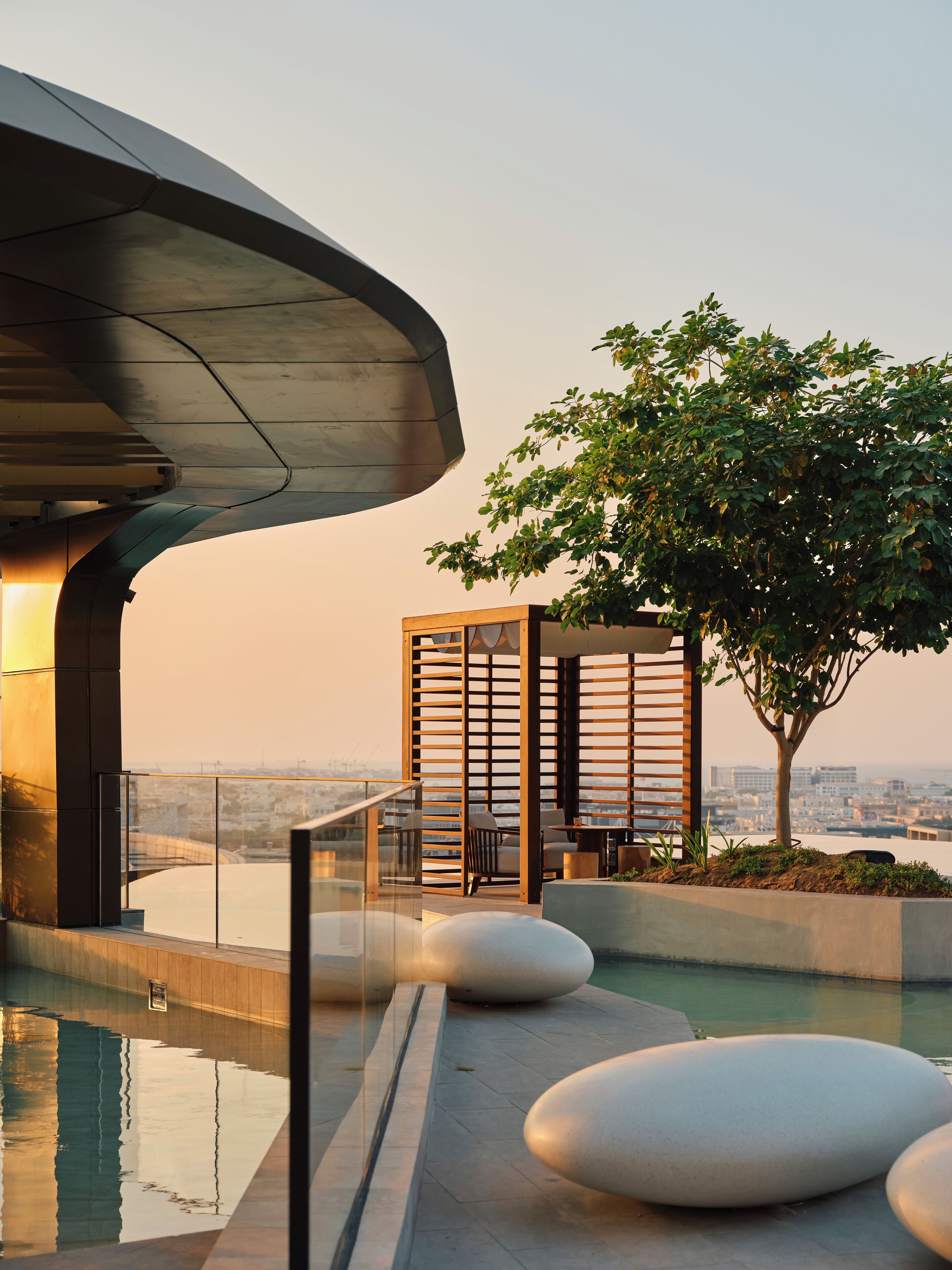 Un espacio exterior moderno con piscina, asientos y vistas panorámicas de la ciudad.