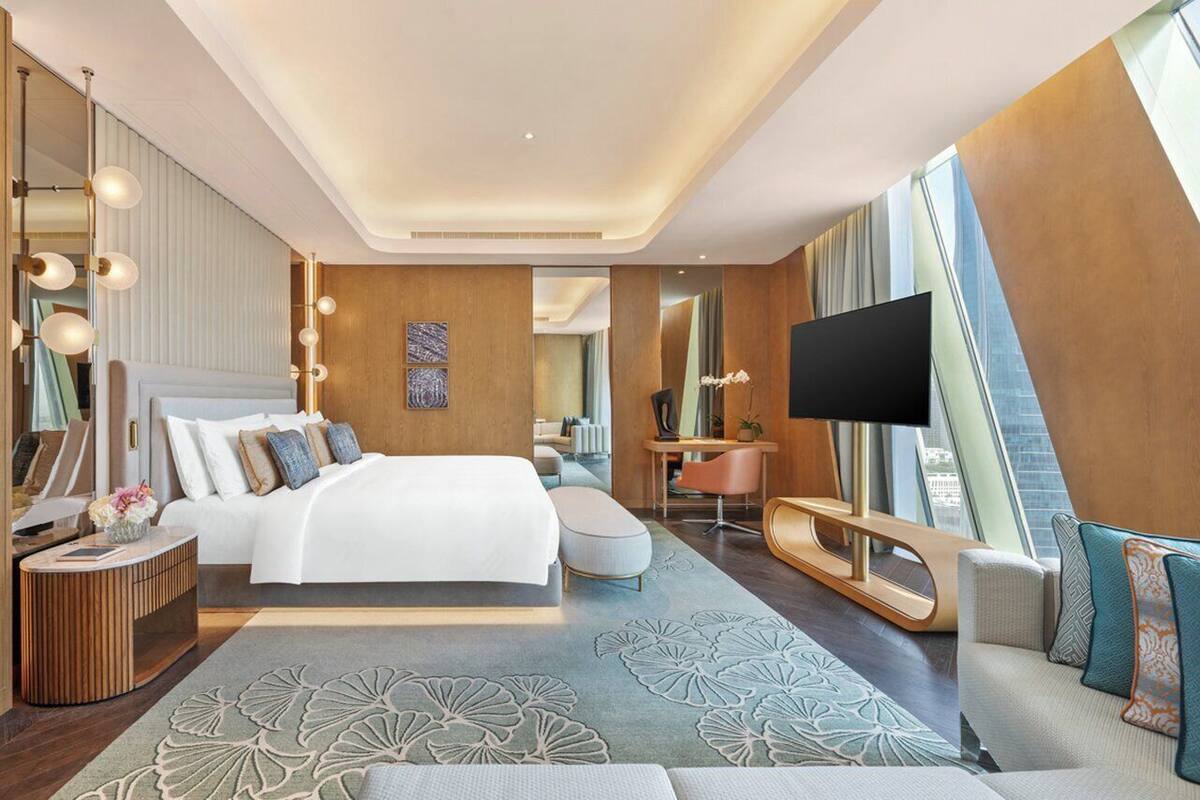 Une chambre d’hôtel moderne dotée d’un grand lit, d’un bureau, d’une télévision et offrant une vue sur la ville.