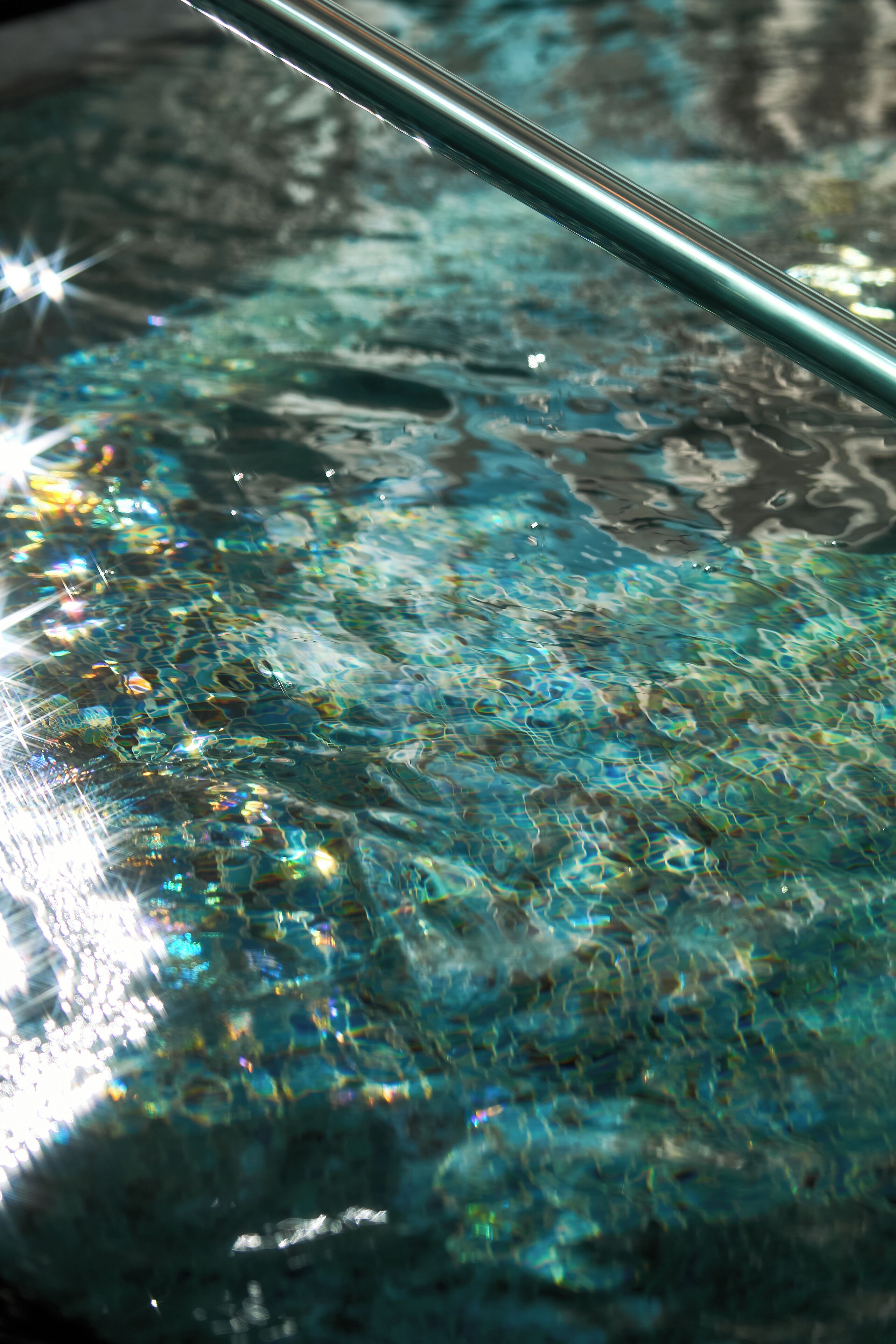 A close-up of a glass surface reflecting light and water.