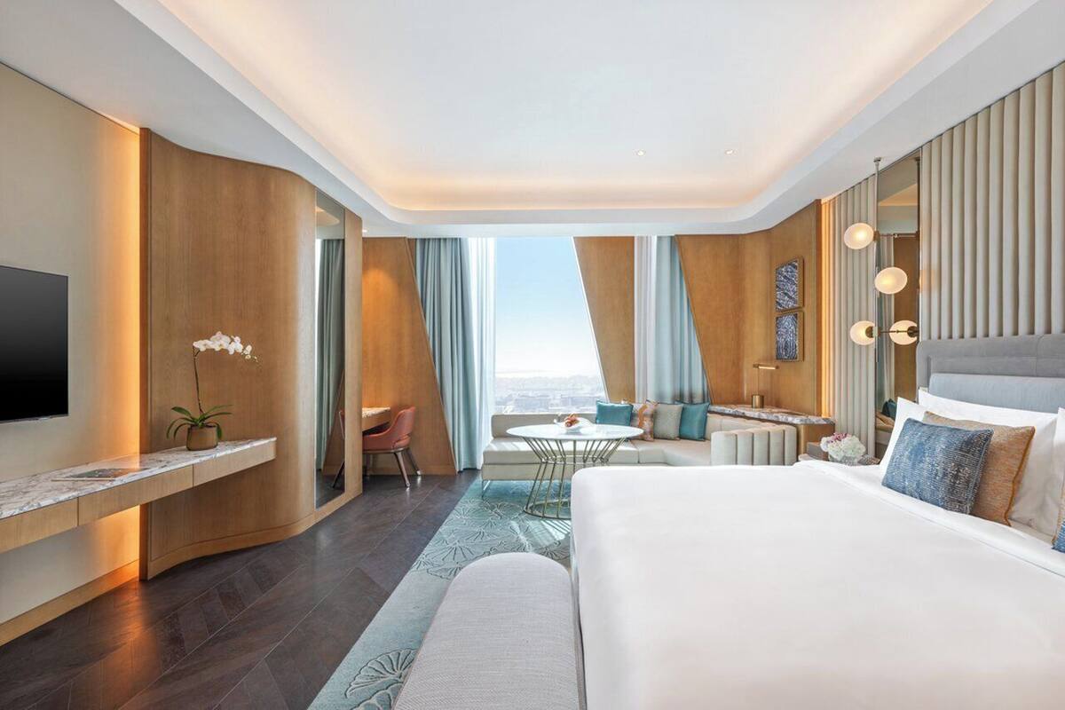 Une chambre d’hôtel moderne dotée d’un grand lit, d’un bureau, d’un coin salon et offrant une vue sur la ville.