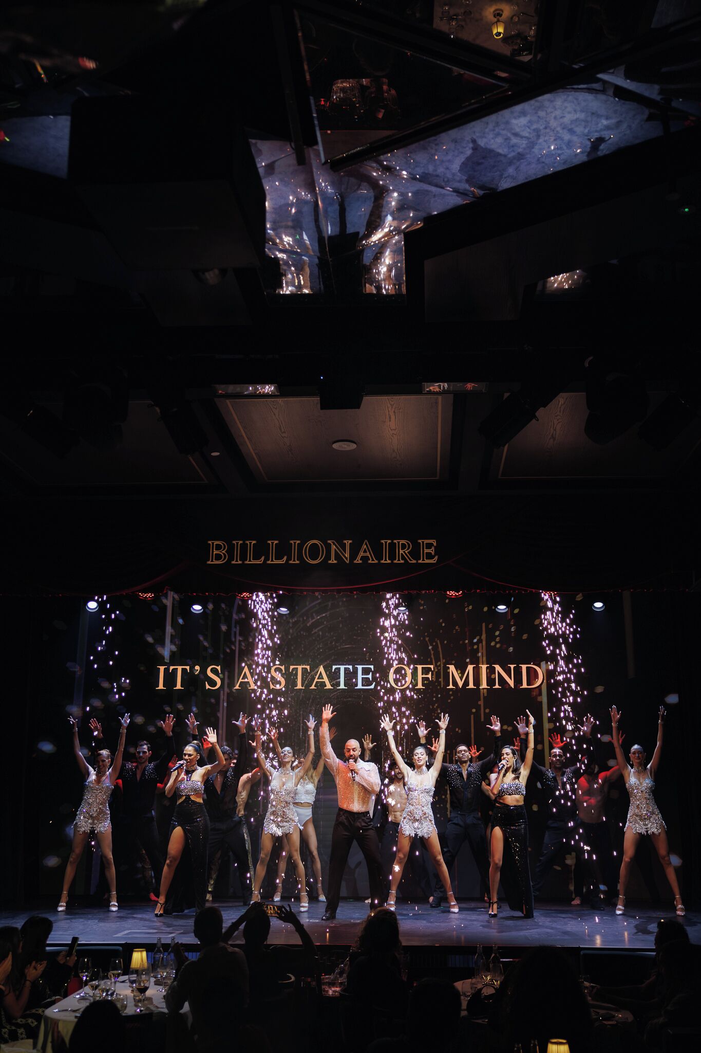 A stage with performers and a sign reading 'BILLIONAIRE IT'S A STATE OF MIND'.