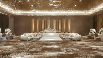 A spacious hall with a central stage, seating arrangements, and a patterned carpet.