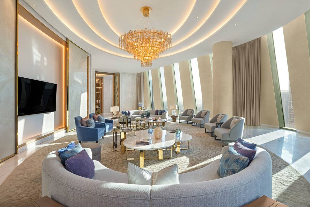 Un salon spacieux agrémenté d’un grand lustre, de plusieurs coins salon et d’un téléviseur à écran plat.