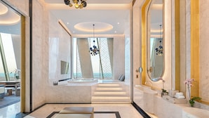 Une salle de bain moderne avec un grand miroir, une baignoire et un lavabo.