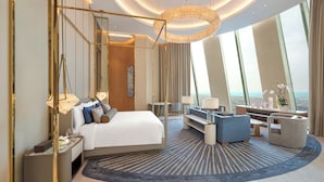 Une chambre d’hôtel moderne dotée d’un grand lit, d’un coin salon et offrant une vue sur l’océan.