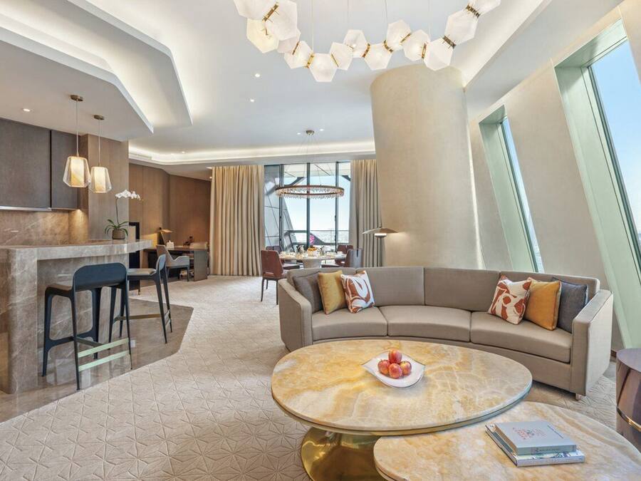 Eine moderne Hotelhalle mit einer gebogenen Couch, einem runden Couchtisch und einem Essbereich.
