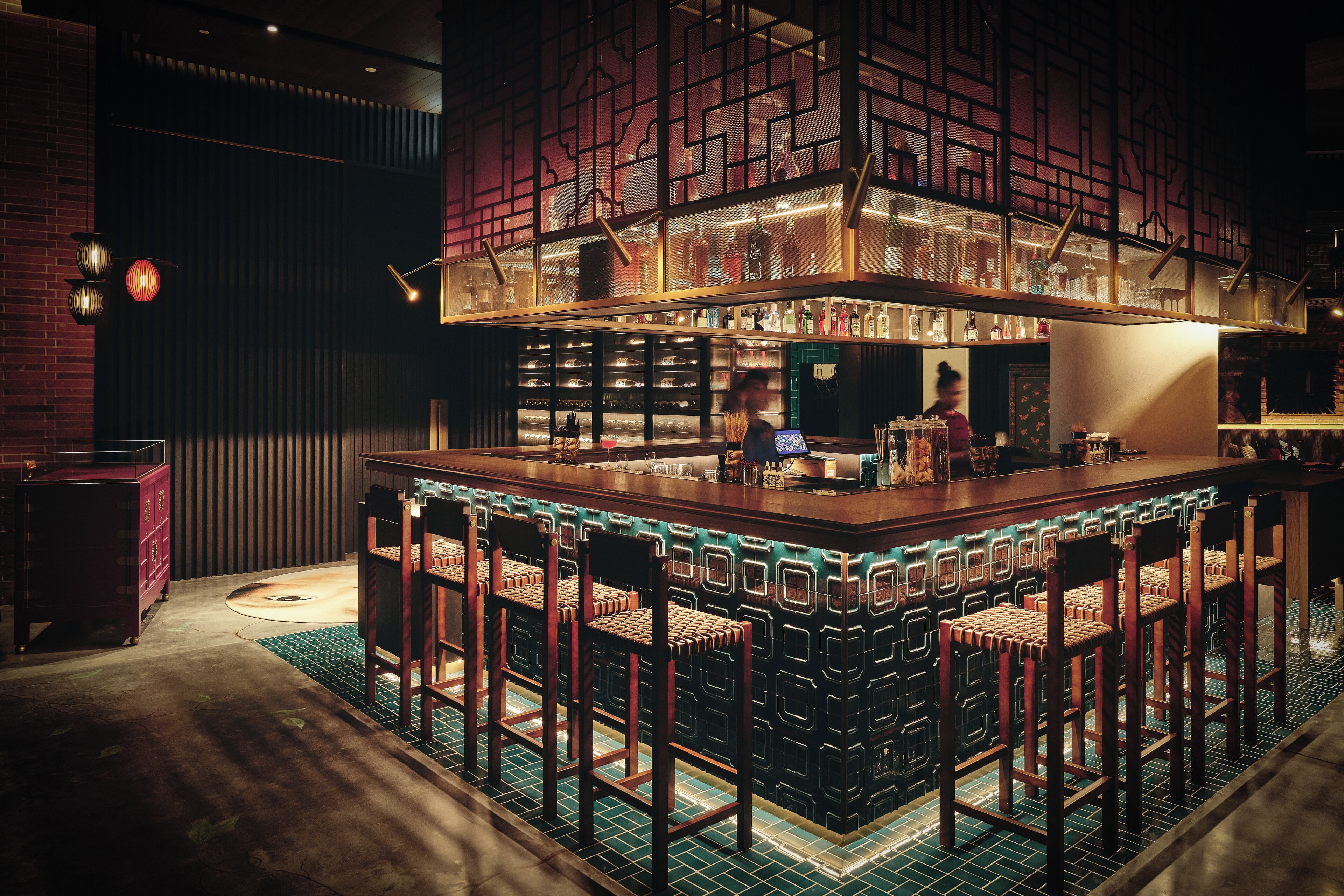 Een bar met een hoge toonbank, meerdere krukken en een goed verlicht interieur.