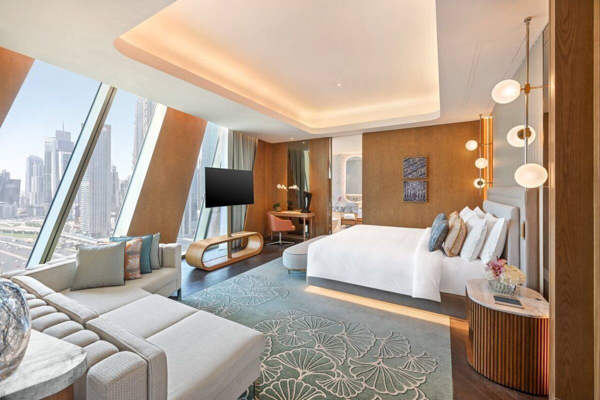 Une chambre d’hôtel moderne dotée d’un grand lit, d’un canapé, d’une télévision et offrant une vue sur la ville.
