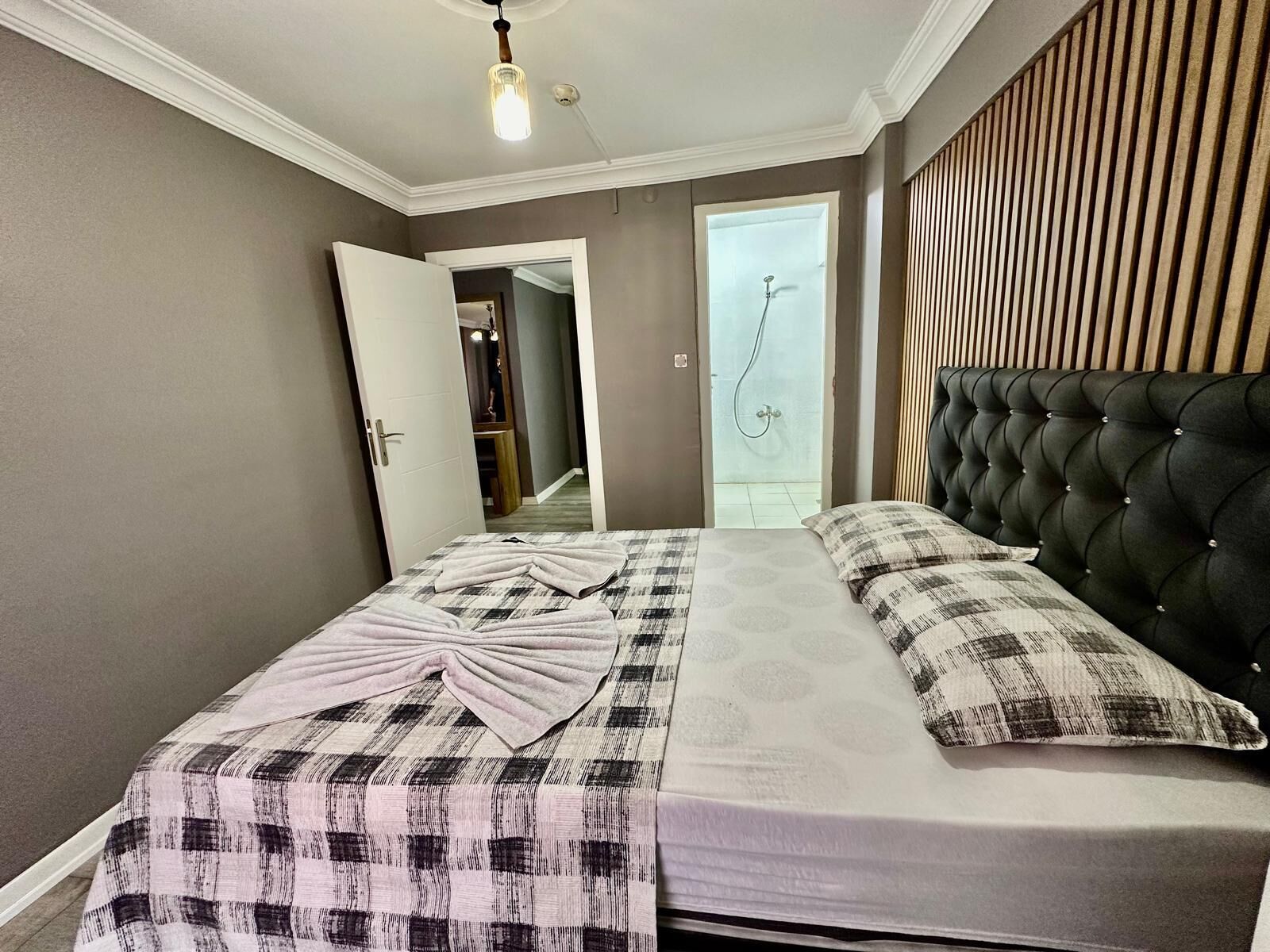 A bedroom with a bed, a headboard, a door, and a shower area.