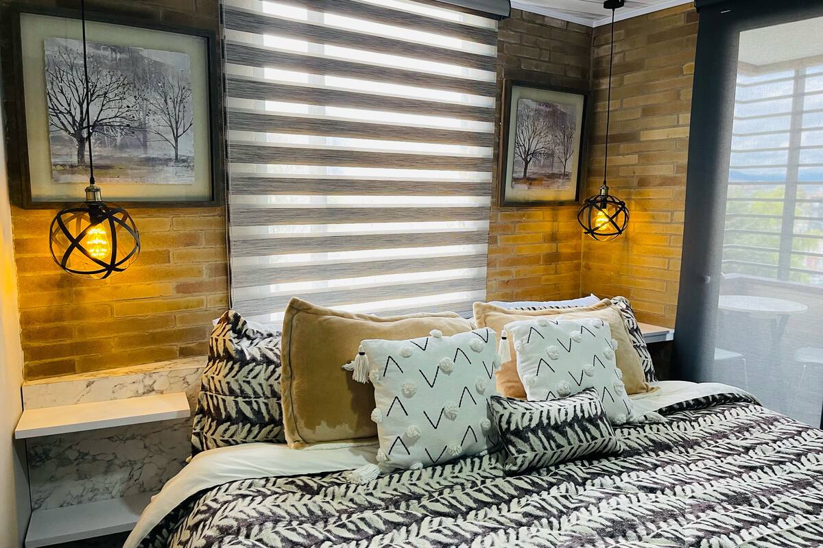 A bedroom with a bed, two wall-mounted lights, and two framed pictures.