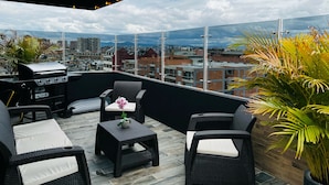 A rooftop terrace with a grill, wicker furniture, and a view of the cityscape. - SUITES H&A 911 (Bogotá)
