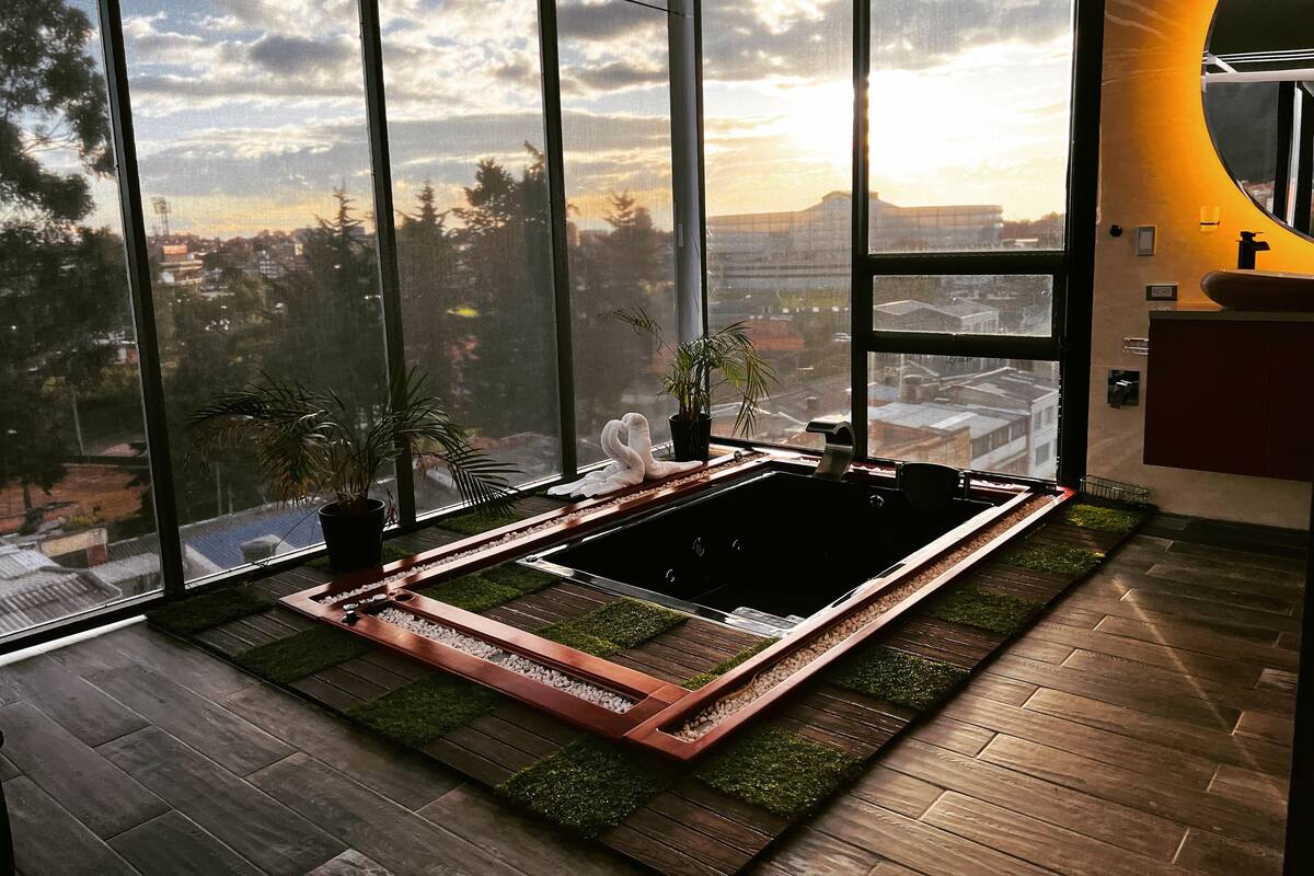A modern bathroom with a large window, a bathtub, and a sink.