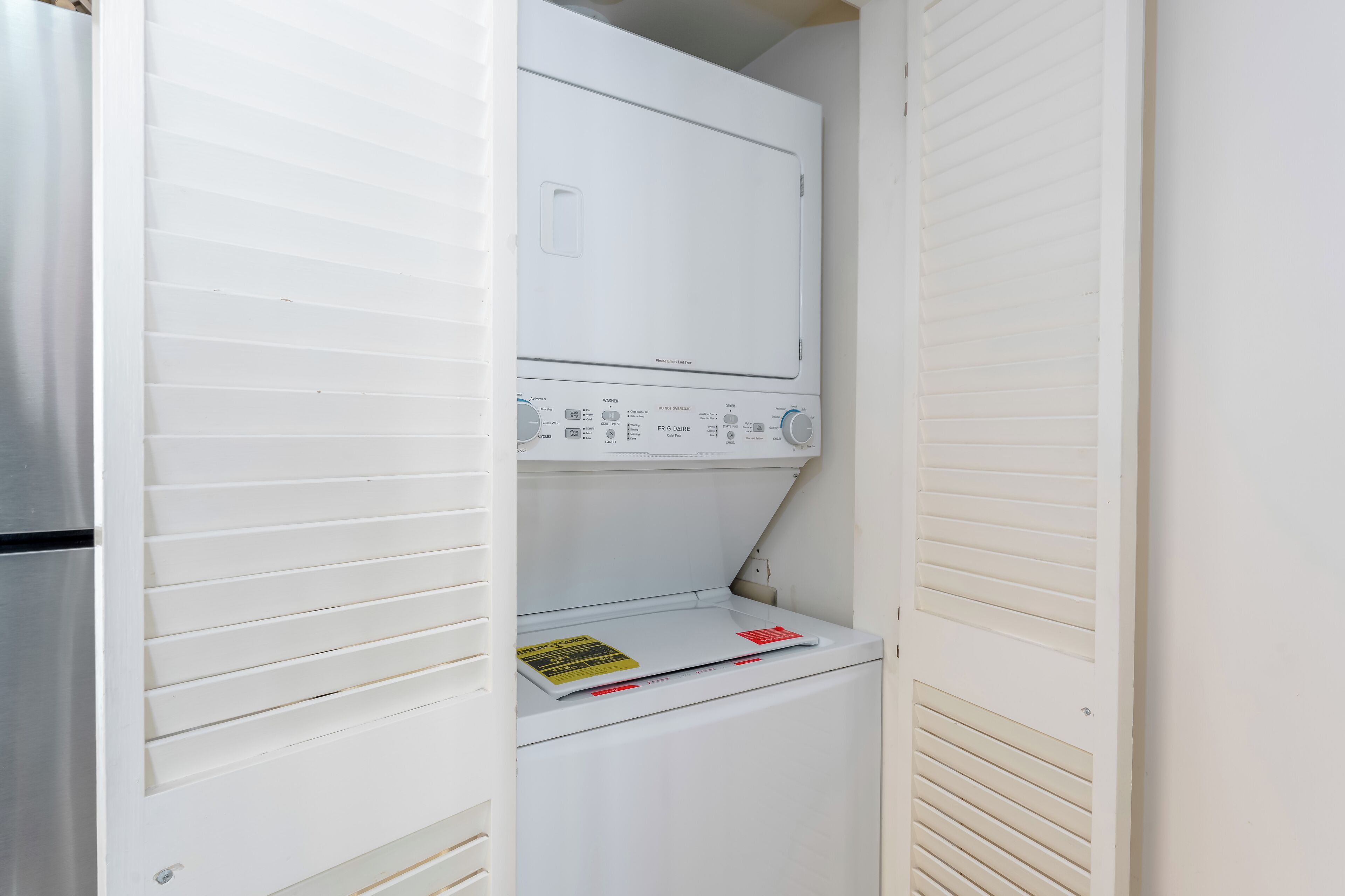 A compact laundry room with a washer and dryer, a small shelf, and a door with a handle.