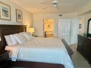 A hotel room with a large bed, a nightstand, a dresser, a ceiling fan, and two framed pictures on the wall. - Towers 8 & 9 8301 - Daytona Beach Oceanfront Vacations, Inc (Ponce Inlet)