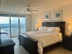 A bedroom with a large bed, two bedside lamps, a ceiling fan, and a view of the ocean through a sliding door. - Luxury at its Finest in this 3/3 Oceanfront #8301 at the Towers in Ponce Inlet (Ponce Inlet)