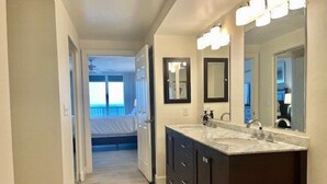 A modern bathroom with dark cabinetry, a large mirror, and a vanity with a sink. - Towers 8 & 9 8301 - Daytona Beach Oceanfront Vacations, Inc (Ponce Inlet)