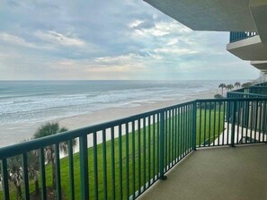 A balcony with a view of the beach and ocean.