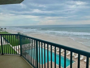 A balcony with a view of the beach and ocean.