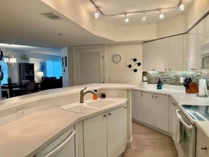 A modern kitchen with white cabinetry, a built-in oven, and a large island with a sink. - Luxury at its Finest in this 3/3 Oceanfront #8301 at the Towers in Ponce Inlet (Ponce Inlet)