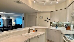 A modern kitchen with white cabinetry, a built-in oven, and a large island with a sink. - Towers 8 & 9 8301 - Daytona Beach Oceanfront Vacations, Inc (Ponce Inlet)