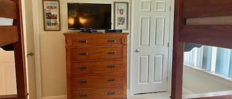 A bedroom with a wooden dresser, a television, and a white door.