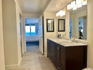 A modern bathroom with dark cabinetry, a large mirror, and a vanity with a sink.