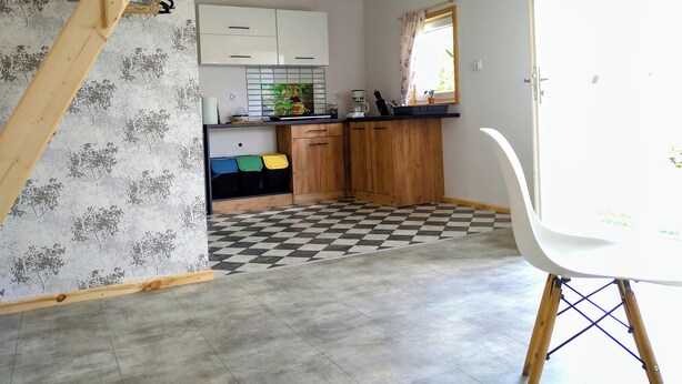 A kitchen with wooden cabinets, a checkered floor, and a white chair. - Urlaub in Masuren - Ferienhaus, Angelurlaub (Iława)