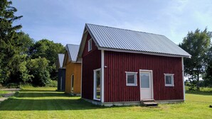 A red wooden cabin with a metal roof, a door, and two windows. - Urlaub in Masuren - Ferienhaus, Angelurlaub (Iława)