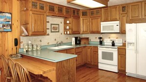 Una cocina con armarios de madera, microondas, estufa y fregadero.