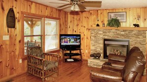 Un salón con paneles de madera, chimenea, televisor y asientos de cuero.