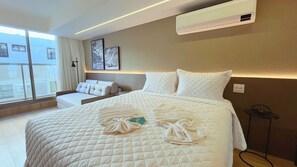 Une chambre d’hôtel avec un grand lit, un canapé, une fenêtre avec des rideaux et des œuvres d’art accrochées au mur.
