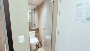 A narrow bathroom with a toilet, a small trash bin, and a glass shower enclosure. - Setai Yacht S4- By Almare Flats (João Pessoa)