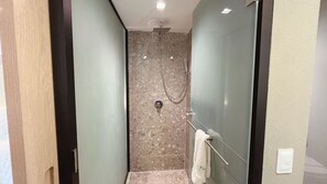 A narrow, tiled shower area with a handheld showerhead and a towel rack.