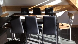 Een moderne eethoek met een hoge plafond en dakraam, met een tafel en stoelen.