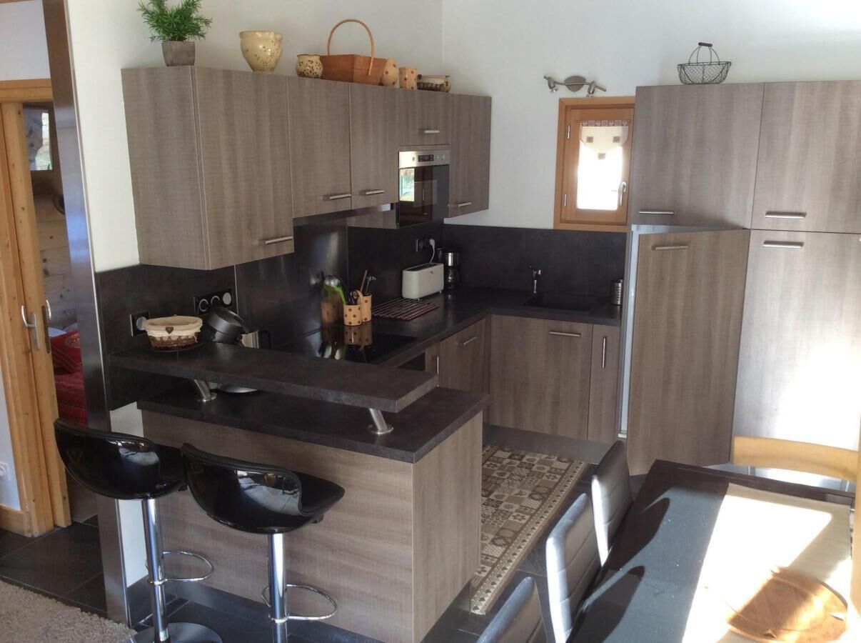 Une cuisine moderne avec des plans de travail sombres, des meubles en bois et un îlot central doté de tabourets de bar.