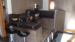 Een moderne keuken met donkere aanrechtbladen, houten kastjes en een centraal eiland met barkrukken.