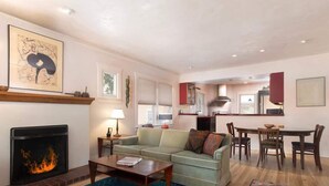 A living room with a fireplace, sofa, coffee table, and a dining area with chairs and a table.