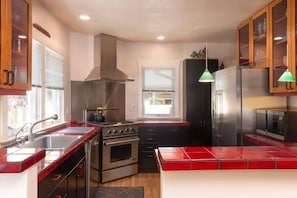 Una cocina moderna con electrodomésticos de acero inoxidable, armarios de madera y una isla con azulejos rojos.