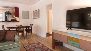 A modern living room with a dining area, a TV, and a kitchen area.